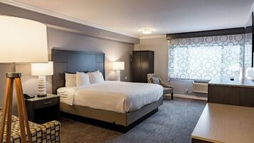 Une chambre d’hôtel moderne équipée d’un grand lit, d’un bureau, d’une chaise et d’une armoire.