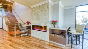 A modern office space with a fireplace, wooden flooring, a desk, and a chair.
