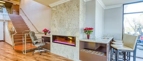 A modern office space with a fireplace, wooden flooring, a desk, and a chair.