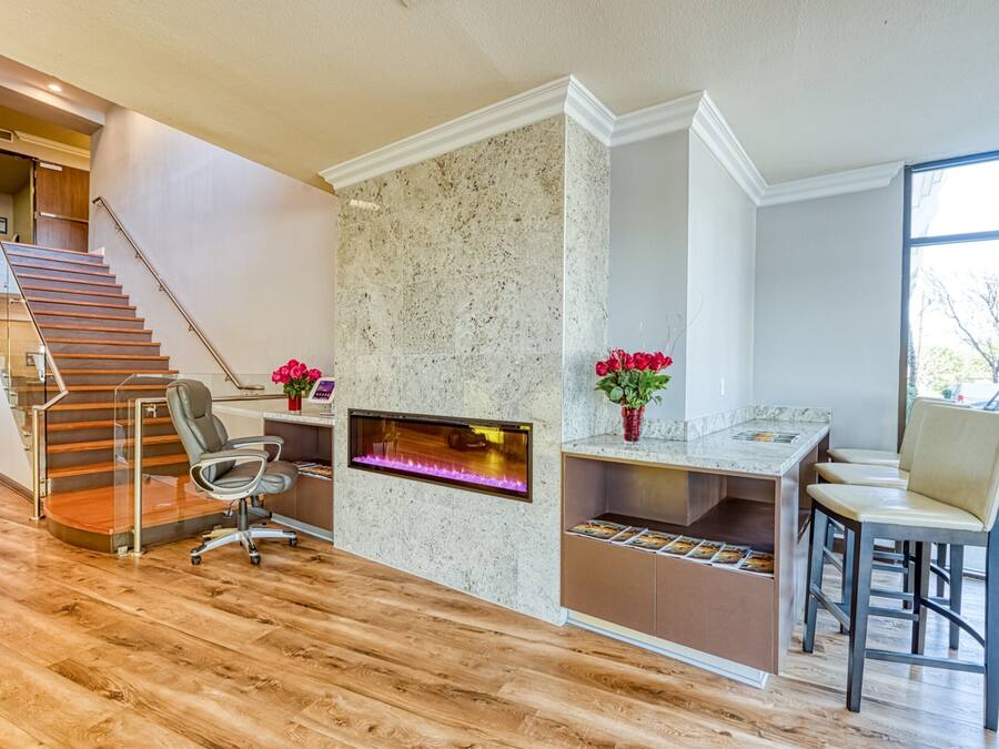 Um espaço de escritório moderno com lareira, piso de madeira, uma mesa e uma cadeira.