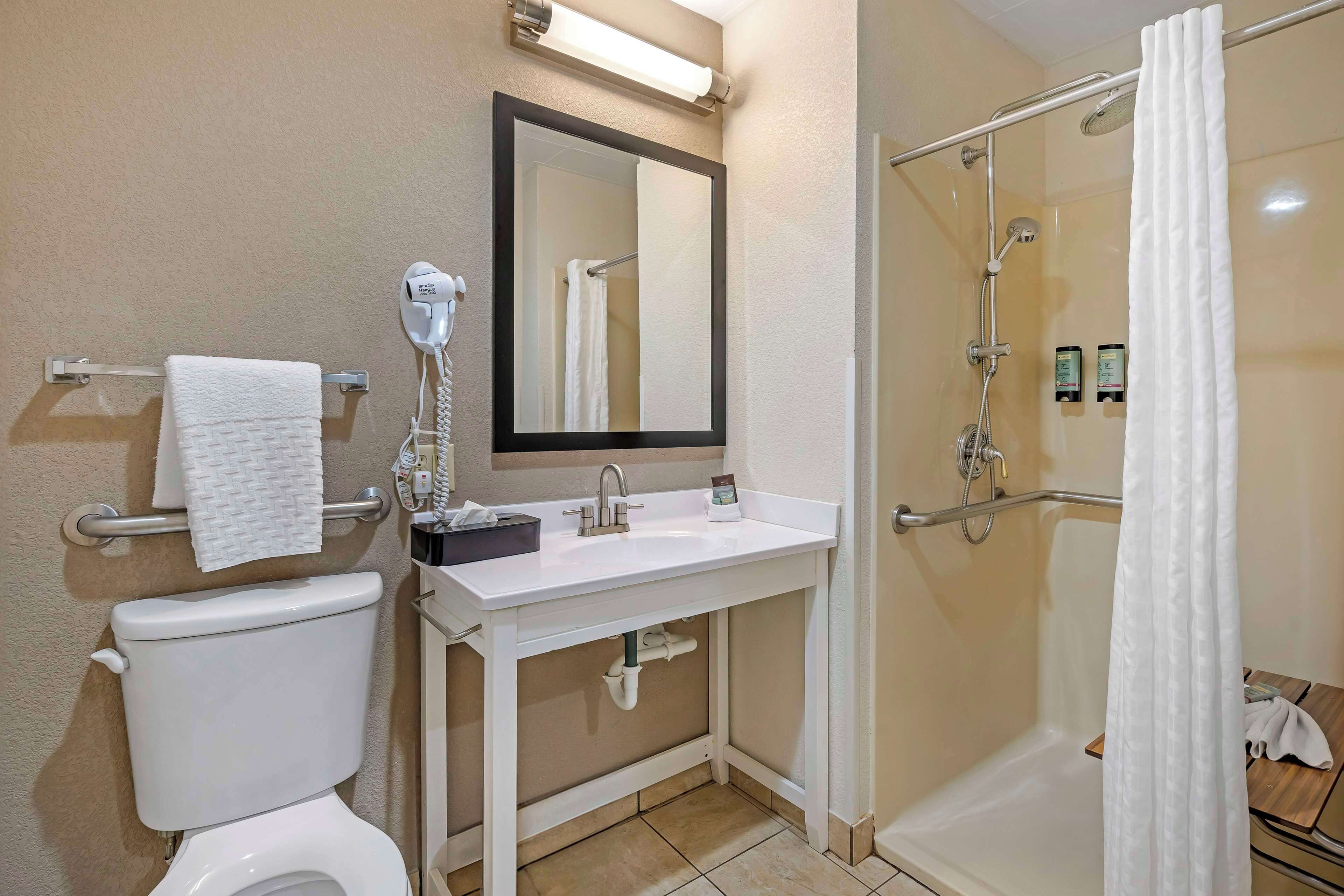 Ein Badezimmer mit Toilette, Waschbecken, Spiegel und Dusche.