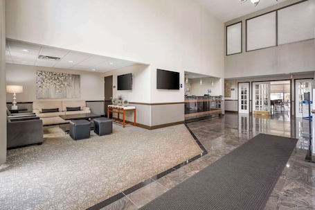 A spacious lobby with a reception desk, seating area, and a large mirror.. Best Western Suites