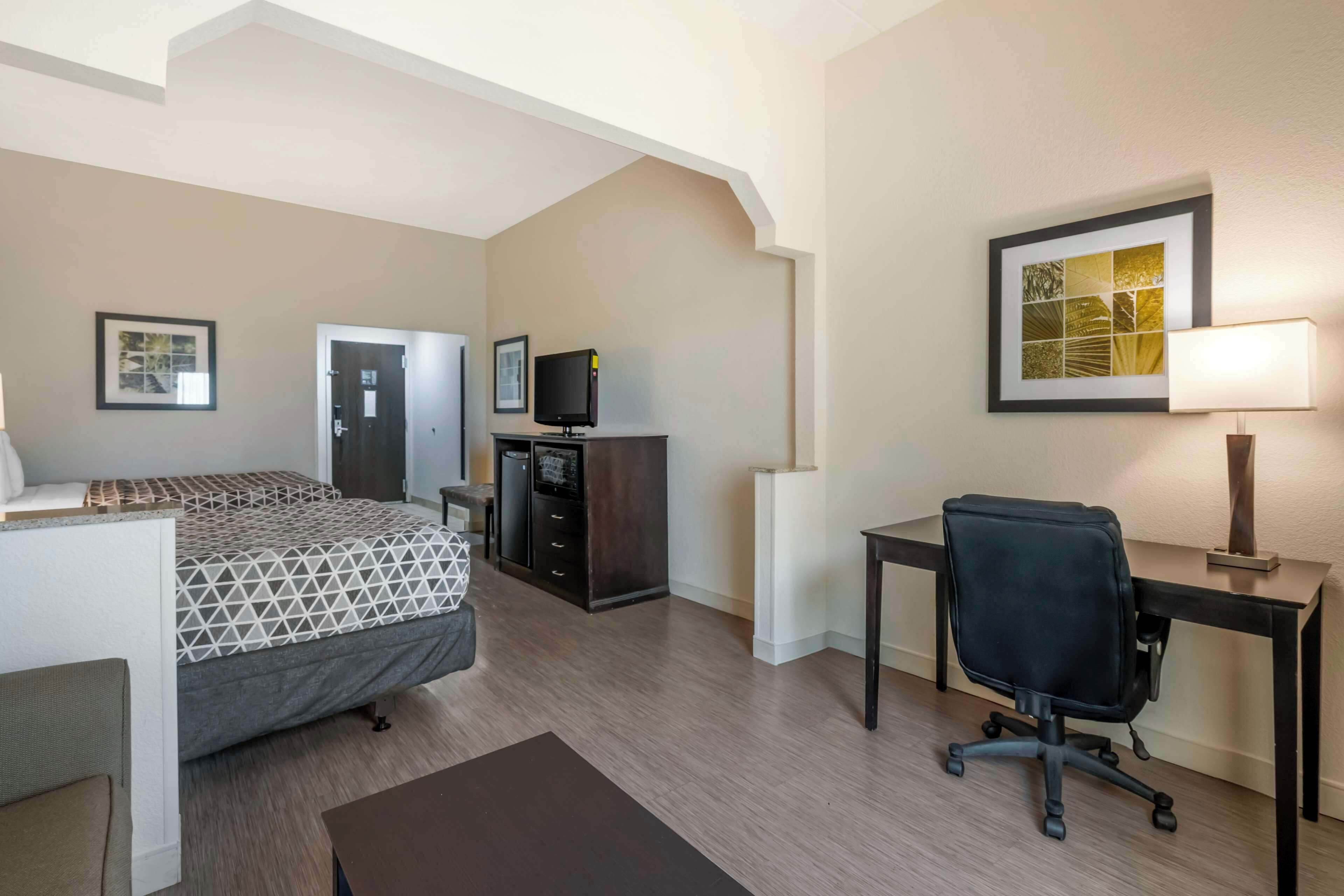 A hotel room with a bed, desk, chair, and a television.
