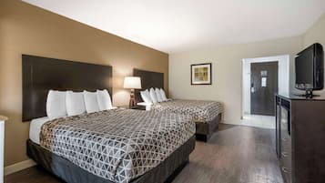 A hotel room with two beds, a TV, a desk, and a door leading to a bathroom.