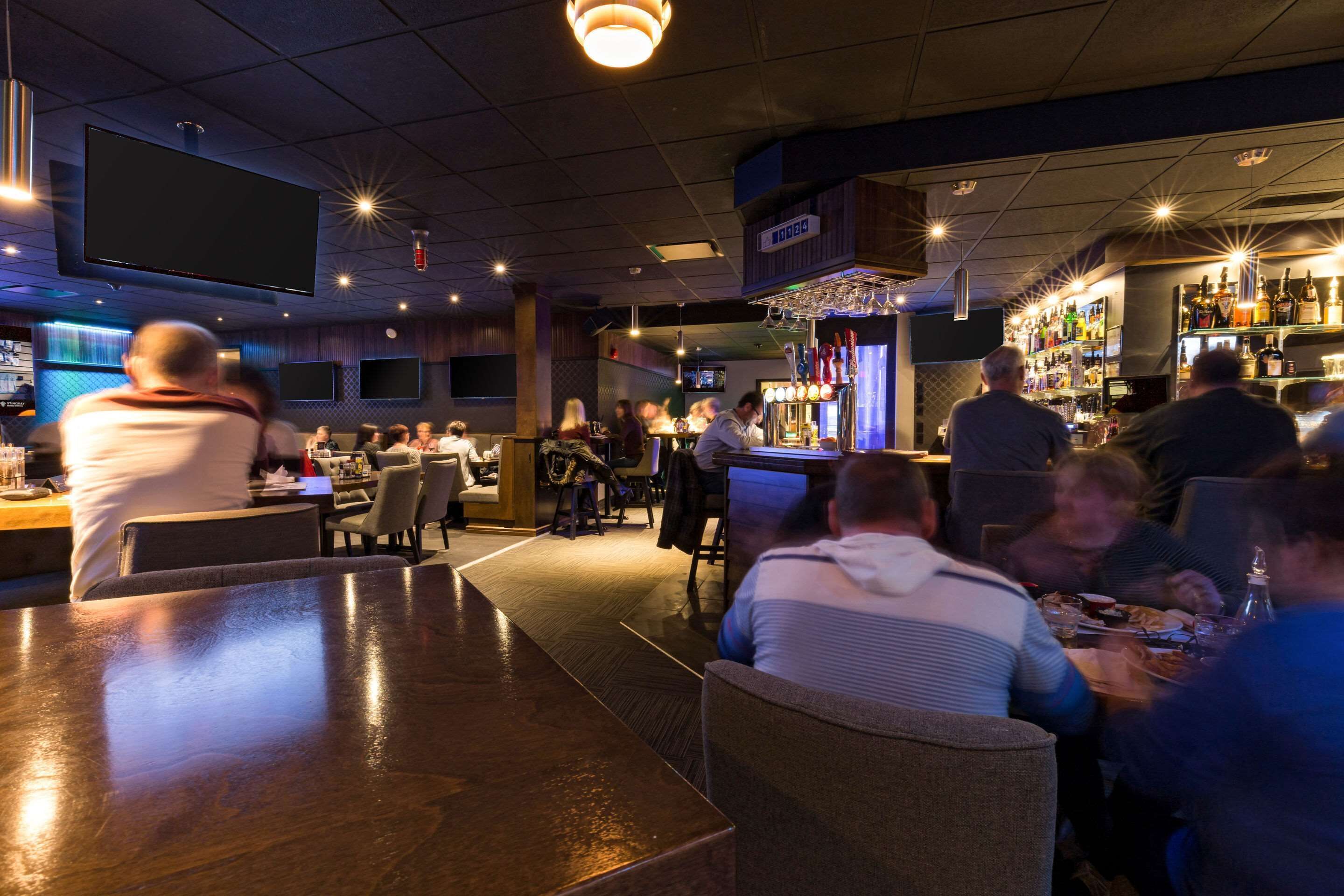 A bar area with seating, a bar counter, and a television screen.