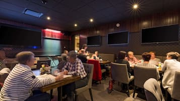 Un restaurant doté de nombreuses tables et chaises, d’un grand écran et d’un décor mural en bois.