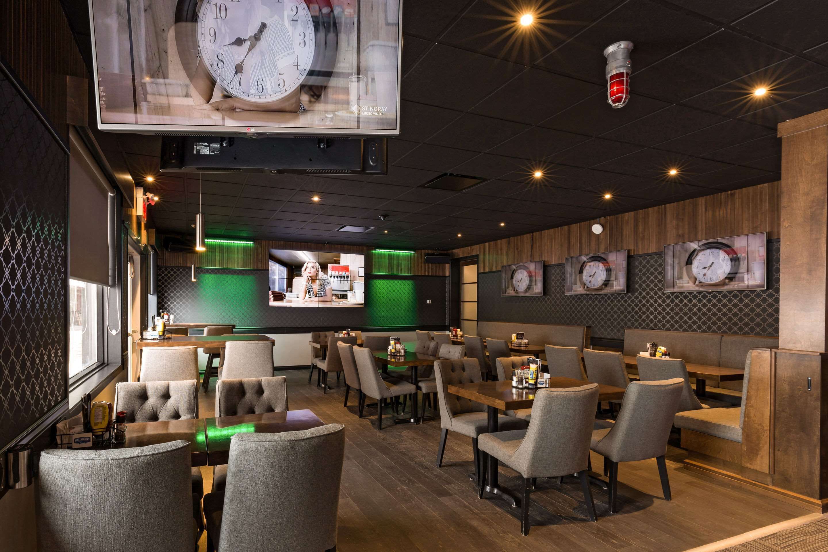 A restaurant with multiple seating areas, including booths and tables, with a large clock and framed pictures on the walls.