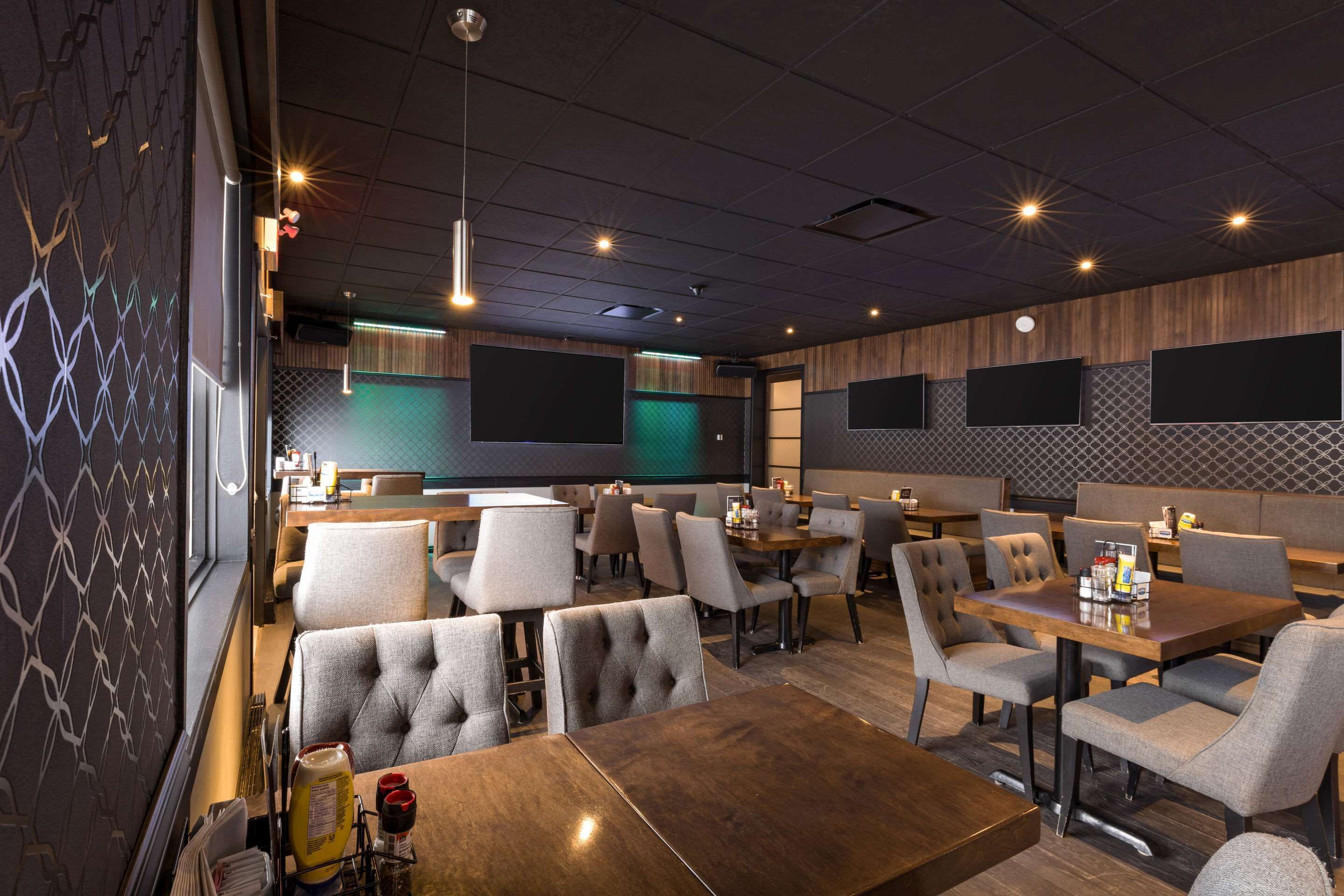 A modern restaurant interior with booths and tables, ambient lighting, and a patterned wall.