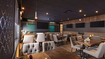 A modern restaurant interior with booths and tables, ambient lighting, and a patterned wall.