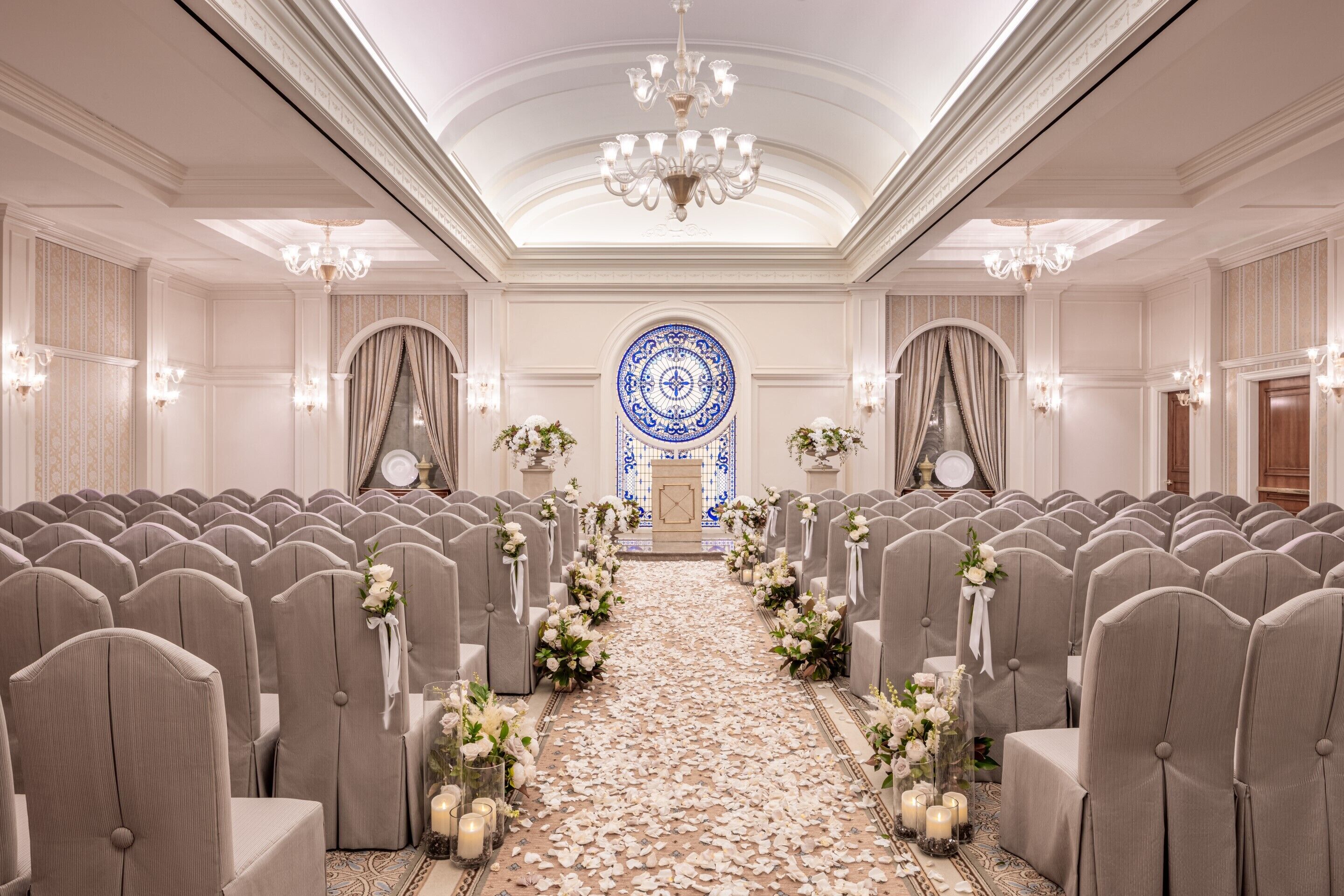 A formal event space with rows of chairs, a central aisle, and a chandelier.
