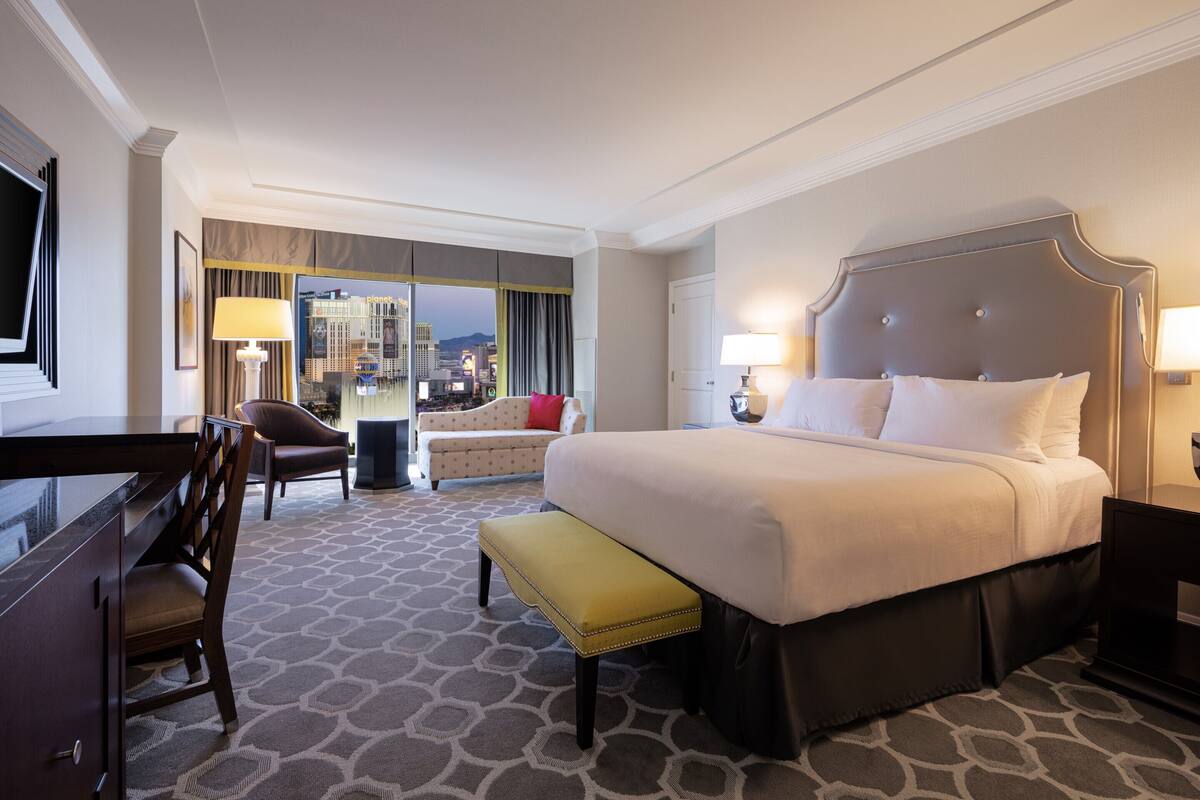 Une chambre d’hôtel avec un grand lit, un bureau, une chaise et un banc.