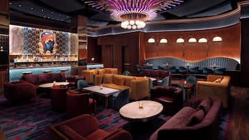 Un espace bar avec un mur décoré de motifs, des tables rondes et des luminaires au plafond au design original.