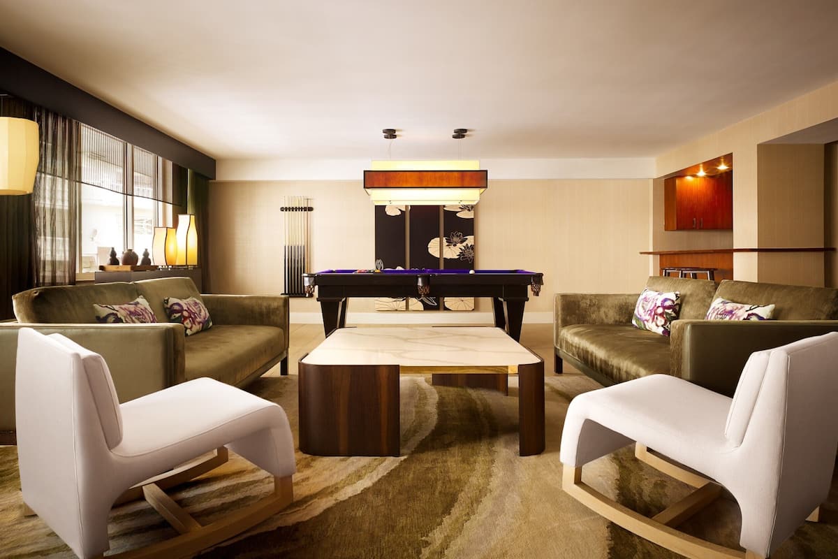 Un salon moderne avec une table de billard, deux canapés, une table basse et une grande fenêtre avec des rideaux.