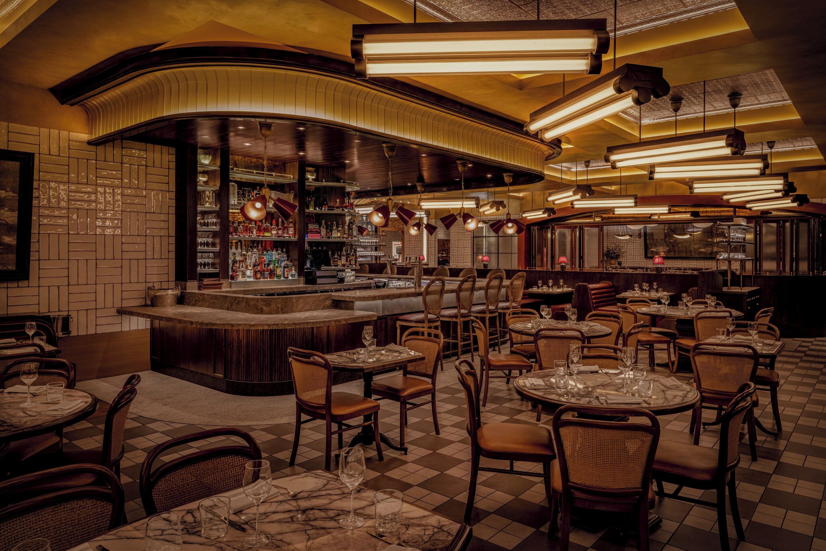 Un ristorante con zona bar, diversi tavoli e sedie.