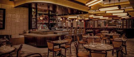 Un ristorante con zona bar, diversi tavoli e sedie.