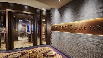 Un interior moderno con un letrero del bar de cigarros Montecristo, que presenta una pared de ladrillo y una alfombra estampada.