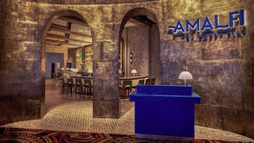 Un espace bar avec un comptoir bleu, des portes en arc de cercle et un bar bien visible où sont exposées les bouteilles.