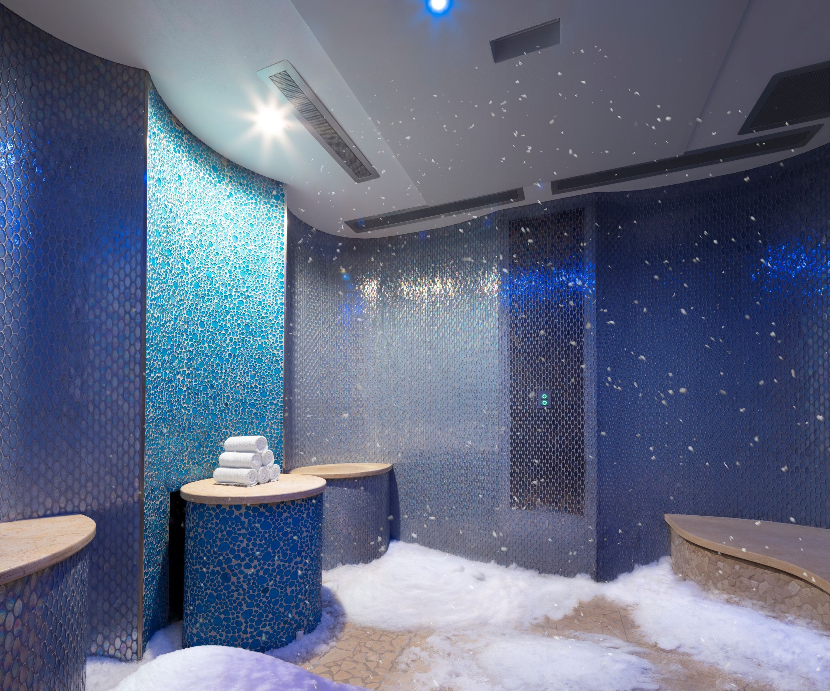 Un cuarto de spa con pared de mosaicos, una fuente de agua y una zona de estar.