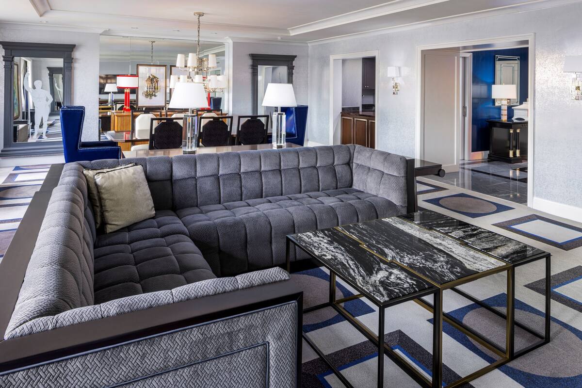 Un salon moderne avec un canapé d’angle, une table basse en marbre et un tapis à motifs.