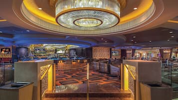 A spacious lobby with a grand chandelier, a bar area, and a modern staircase.