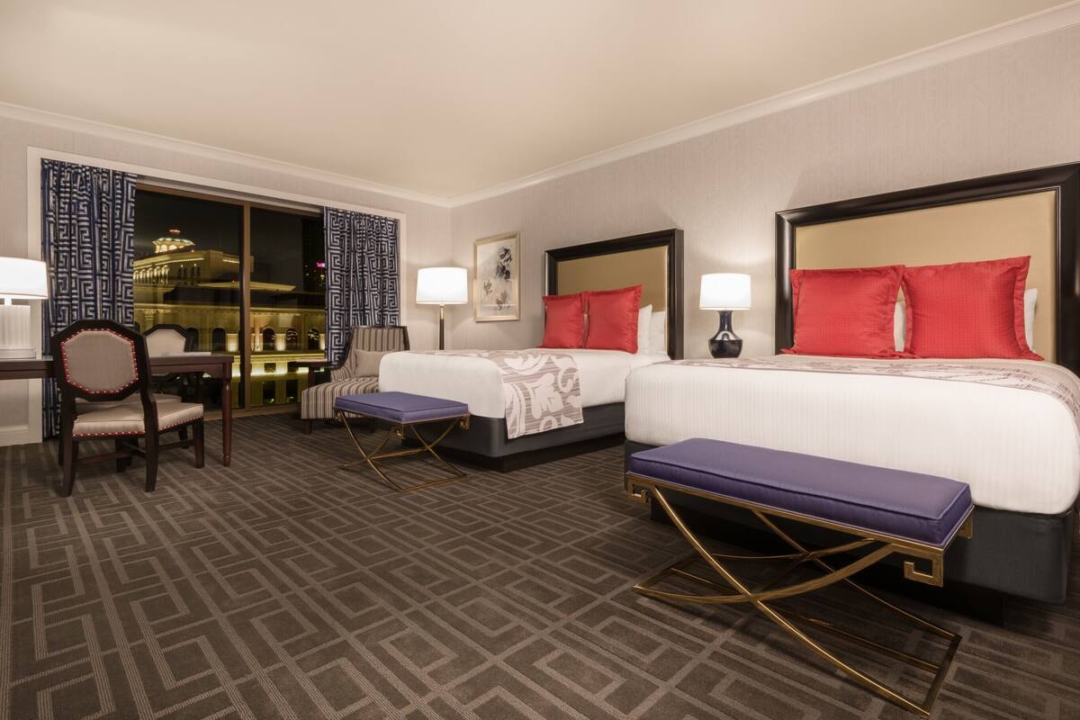 Une chambre d’hôtel avec deux lits, un bureau et une chaise.