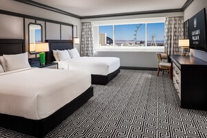 A hotel room with two beds, a desk, a chair, a large window with a view of a Ferris wheel, and a framed sign on the wall.