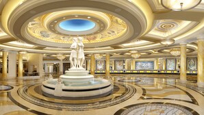 Un lobby imponente con una fuente central, techo ornamentado y obras de arte clásicas.
