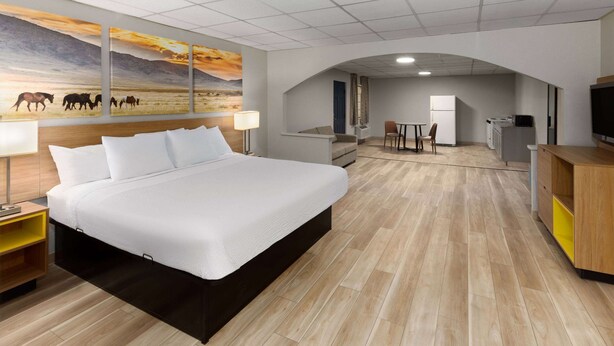 Een hotelkamer met een groot bed, een bureau, een stoel, een televisie en een schilderij aan de muur.