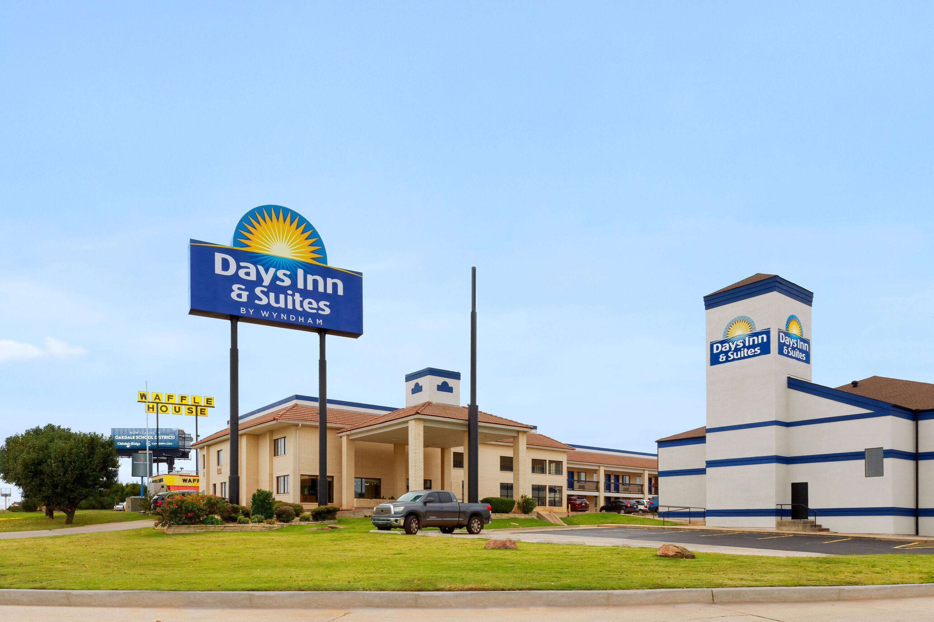 Edificio de Days Inn & Suites con un letrero llamativo, un estacionamiento y un Waffle House cerca.