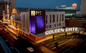 L’extérieur de l’hôtel Golden Gate, avec son enseigne bien visible, son architecture moderne et un parking où l’on peut voir des voitures.