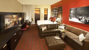 Une chambre d’hôtel avec un grand lit, un canapé en cuir, une télévision, un minibar et une vue sur la ville.