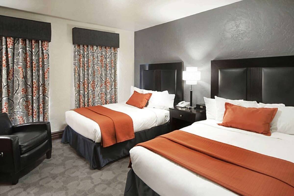 Habitación de hotel con dos camas, un escritorio y una silla.