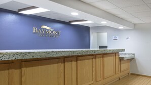 A reception desk with a blue wall and a granite countertop. - Baymont by Wyndham Oklahoma City/Quail Springs (Oklahoma City)