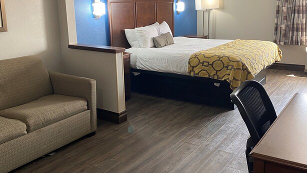 A hotel room with a bed, a sofa, a desk, and a chair. - Baymont by Wyndham Oklahoma City/Quail Springs (Oklahoma City)