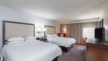 A hotel room with two beds, a TV, a desk, and a chair.