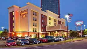 Egy Hampton Inn szálloda, amelyhez több parkolóhely tartozik, és egy nagy amerikai zászló díszíti.