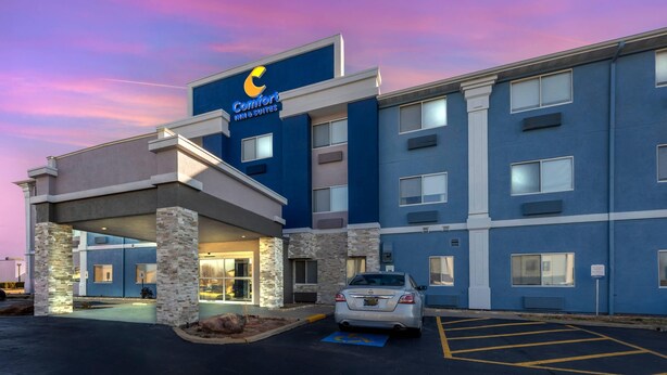 Un hôtel à la façade bleue, doté d’une entrée couverte et d’un parking.