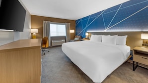 Une chambre d’hôtel équipée d’un lit, d’un bureau, d’une télévision et offrant une vue sur l’extérieur.