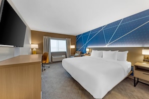 Hotellihuone, jossa on sänky, työpöytä, televisio ja näkymä ulos.