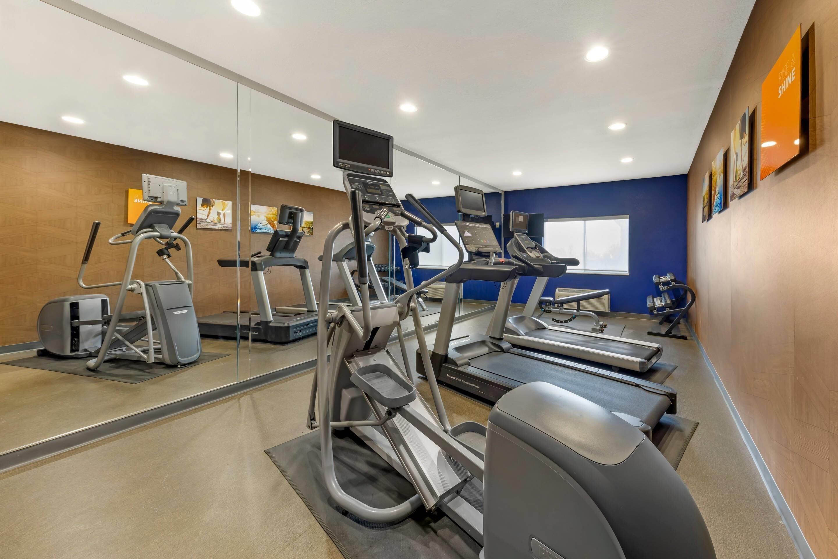 A gym with treadmills, elliptical machines, and a stationary bike.