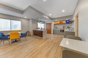 A modern kitchen with a central island, a dining area with chairs, and a large window. - Comfort Inn & Suites Oklahoma City North - Quail Springs (Oklahoma City)