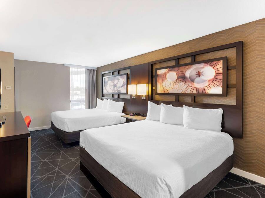 Ein Hotelzimmer mit zwei Betten, einem Schreibtisch und einem Fernseher.
