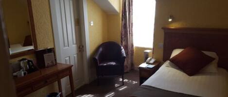 A hotel room with a bed, a chair, a desk, and a mirror.