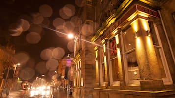 Vista nocturna de una calle con un edificio que muestra un letrero que dice 'RESTAURANT ASH'.