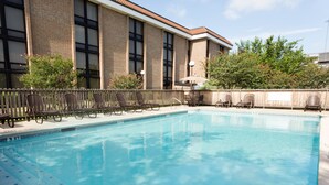 A swimming pool with lounge chairs and a building with large windows in the background.