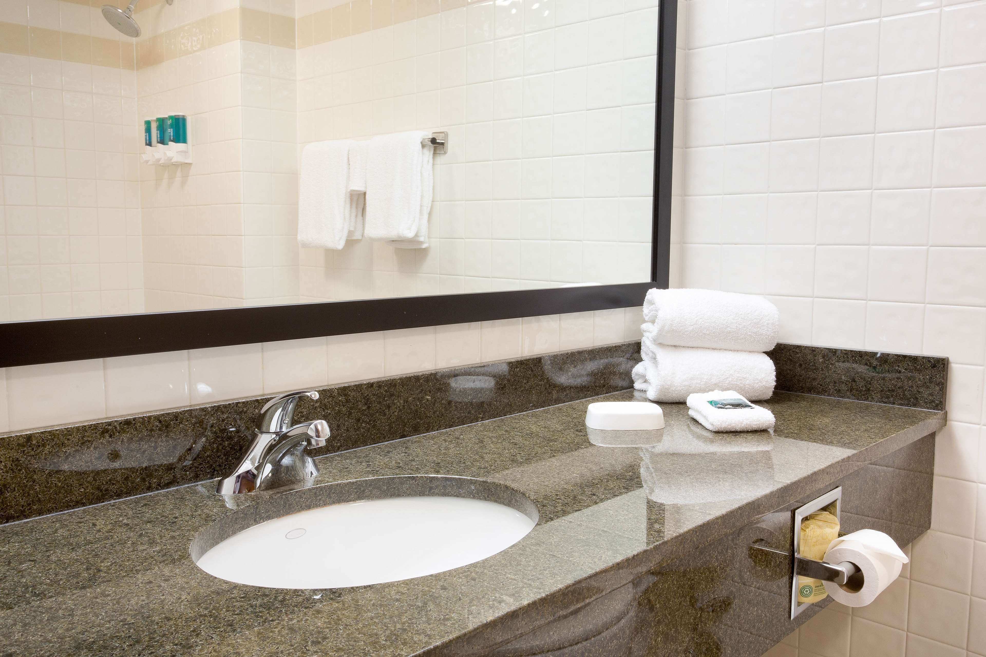 A bathroom with a sink, mirror, and towel rack.