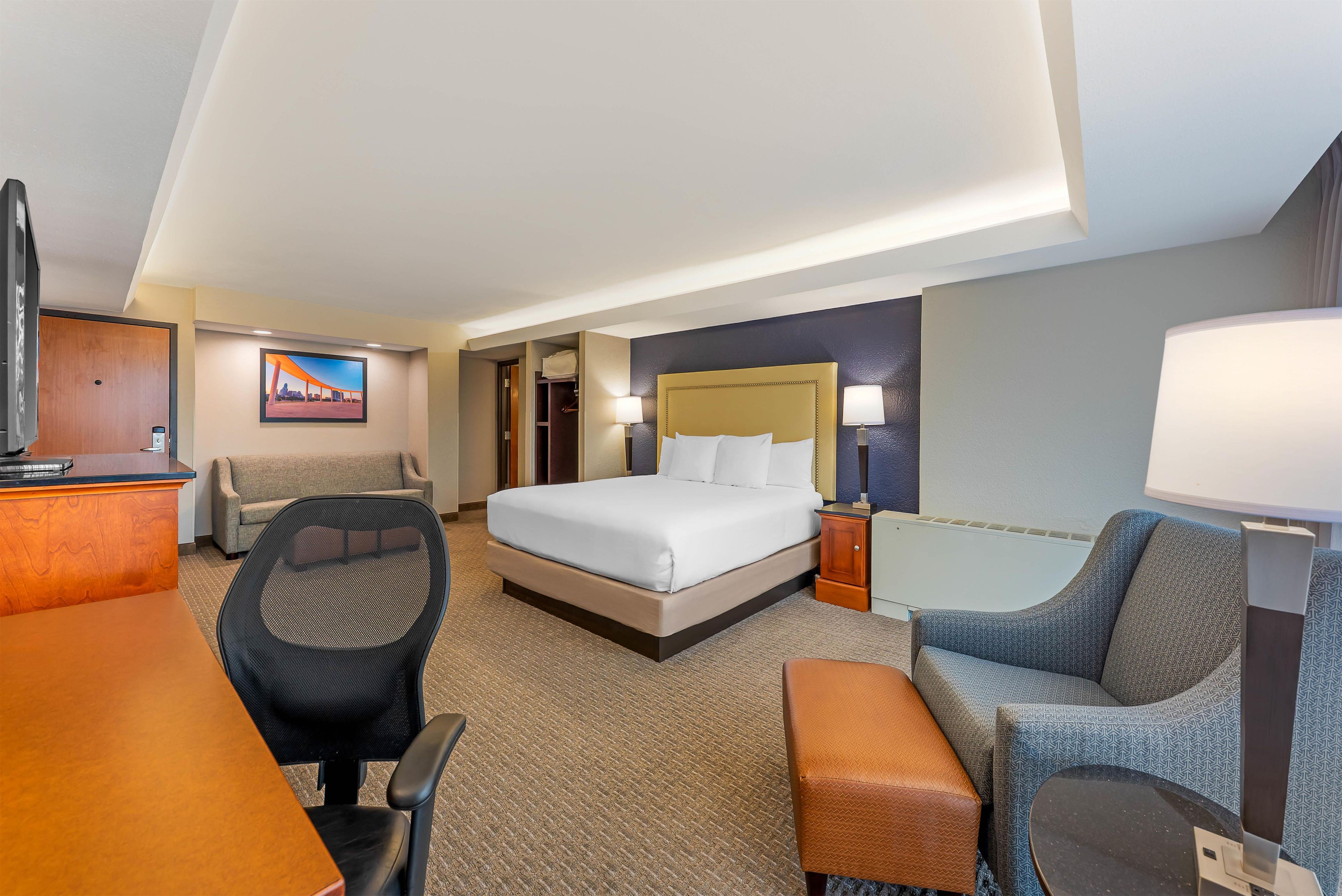 Habitación de hotel con cama, escritorio, silla y vistas a la ciudad.