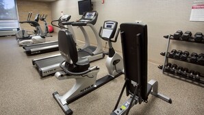 A gym with treadmills, elliptical machines, a stationary bike, and a rack of dumbbells.