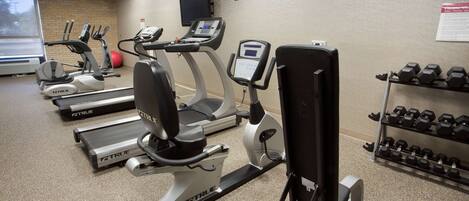 A gym with various exercise equipment including treadmills, elliptical machines, and free weights.