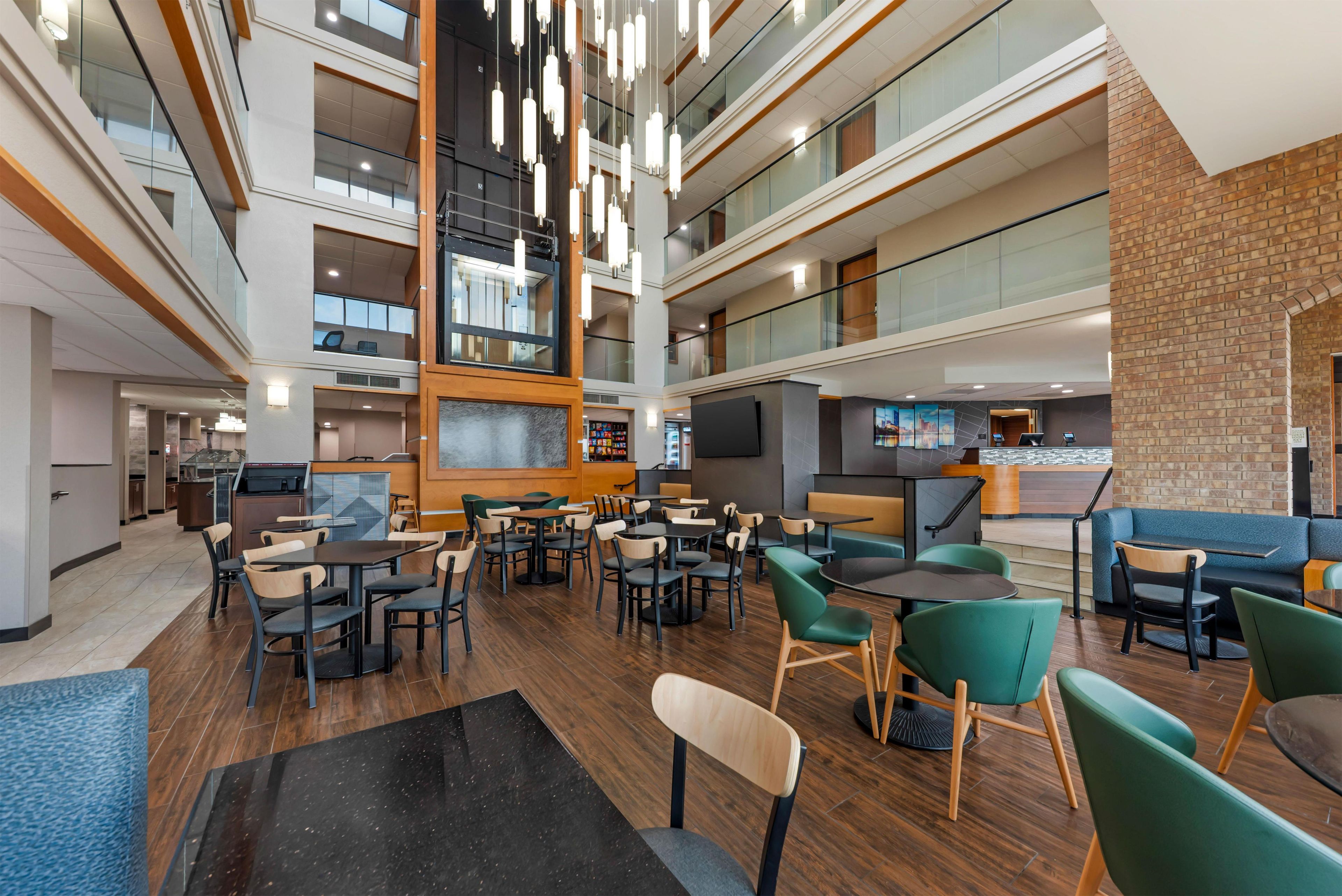 A multi-level hotel lobby with a central atrium, seating areas, and a reception desk.